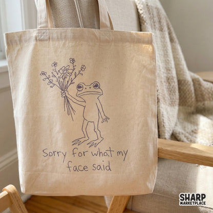 Digital graphic of a grumpy frog holding flowers with the sarcastic text Sorry for what my face said, suitable for DIY gifts, tumblers, and wall art.
