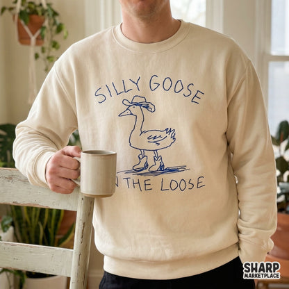 A digital design featuring a sketchy blue goose in cowboy gear with the phrase Silly Goose On The Loose, perfect for custom t-shirts or stickers.
