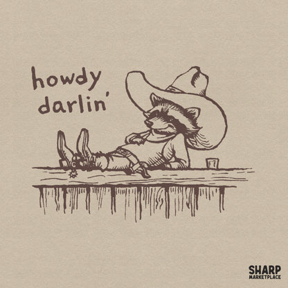 Vintage sepia line art of a laid-back raccoon wearing a cowboy hat and spurs on a fence with the text Howdy Darlin for country style sublimation.