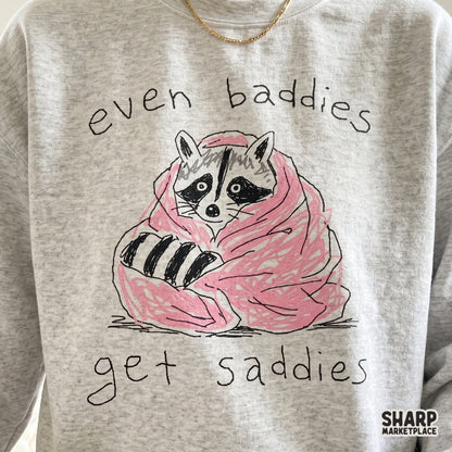 Cute, relatable raccoon design featuring a cozy pink blanket and handwritten typography, suitable for creating unique apparel and mental health art.
