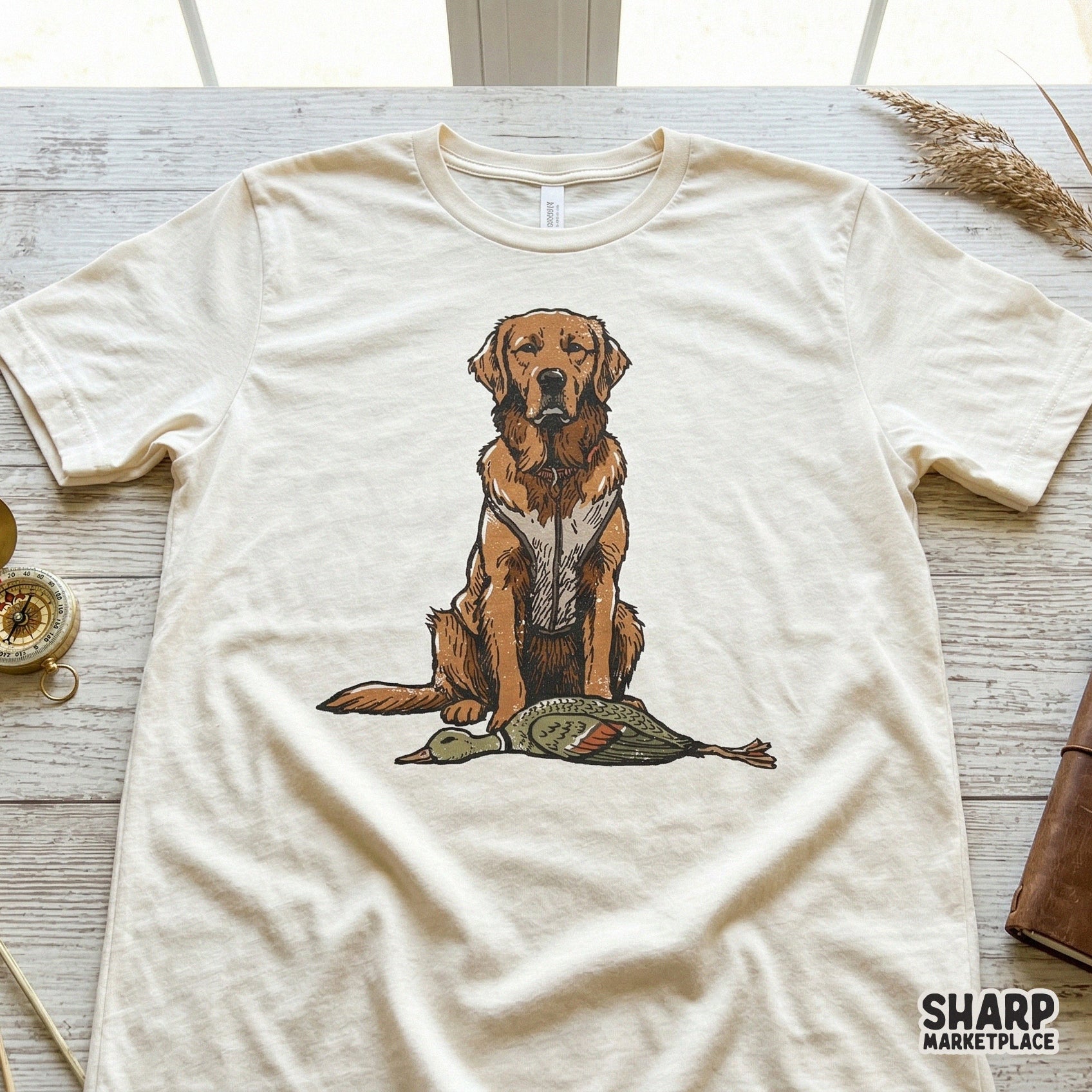 Detailed retriever and duck hunting illustration printed on a cream colored t-shirt, perfect for outdoor themed apparel and western style designs.