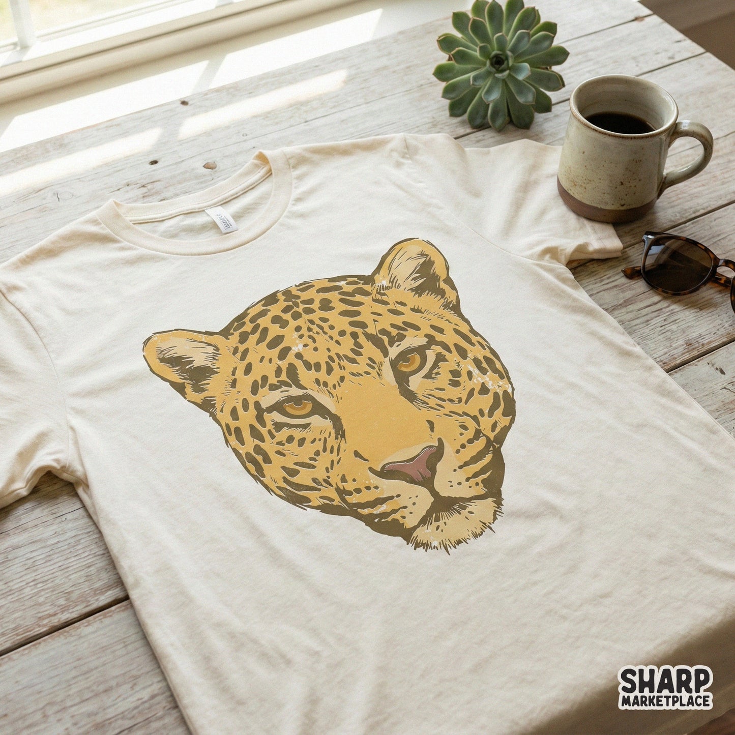 Distressed leopard head graphic printed on a cream-colored t-shirt, showcasing a bold and rugged big cat design for custom apparel projects.