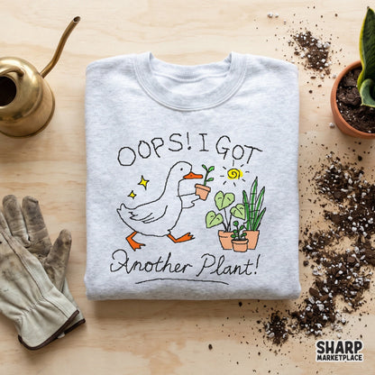 Cute goose gardener artwork with the text Oops! I Got Another Plant! featuring yellow sparkles and potted plants for trendy apparel printing.