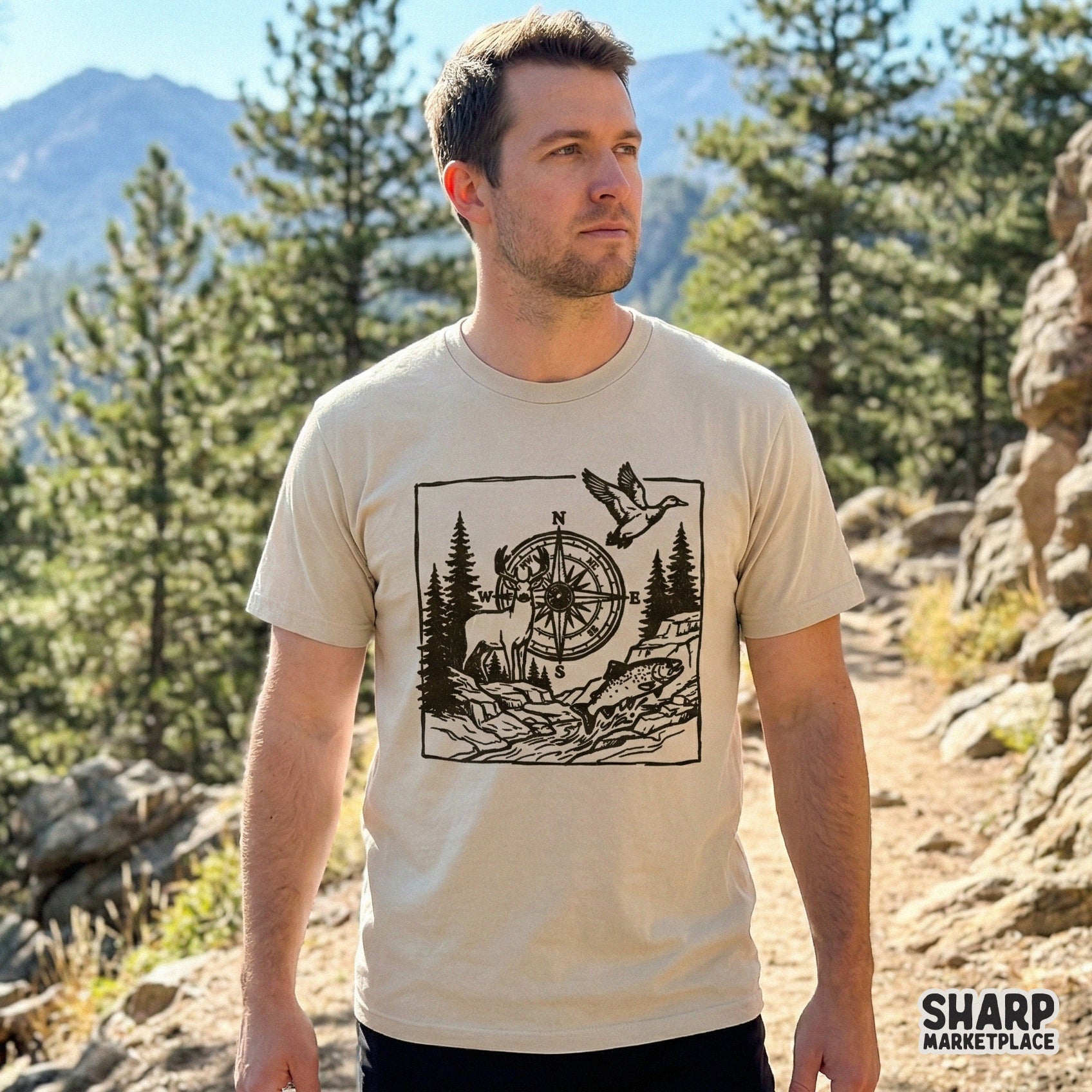 Rustic woodblock-style outdoor graphic printed on a beige t-shirt, showcasing a compass, whitetail deer, mallard duck, and trout for nature lovers.