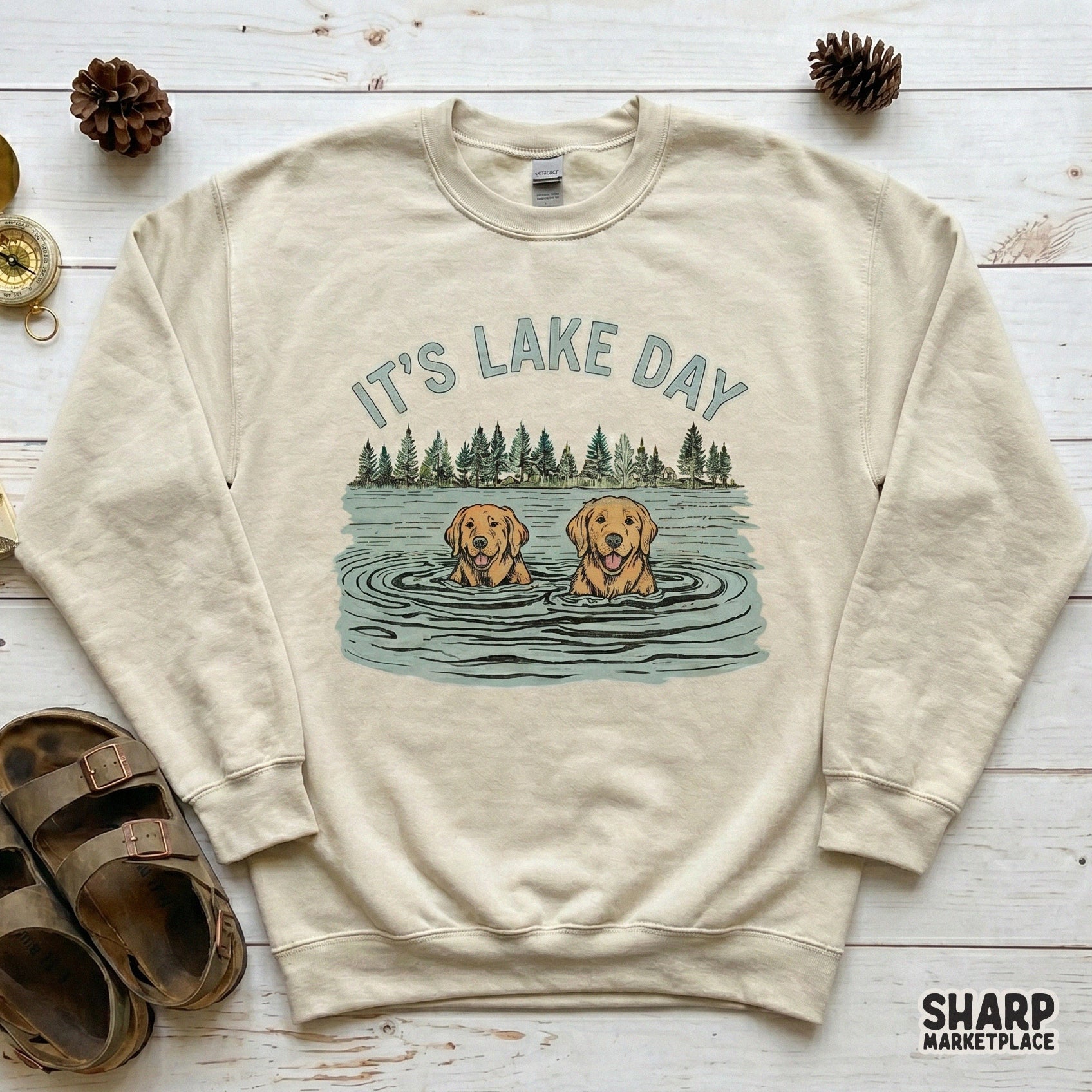 Digital download graphic featuring two swimming dogs and pine trees with the text It's Lake Day ideal for creating stickers, tumblers, and vacation gifts.