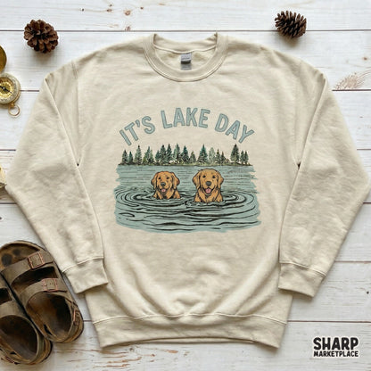 Digital download graphic featuring two swimming dogs and pine trees with the text It's Lake Day ideal for creating stickers, tumblers, and vacation gifts.