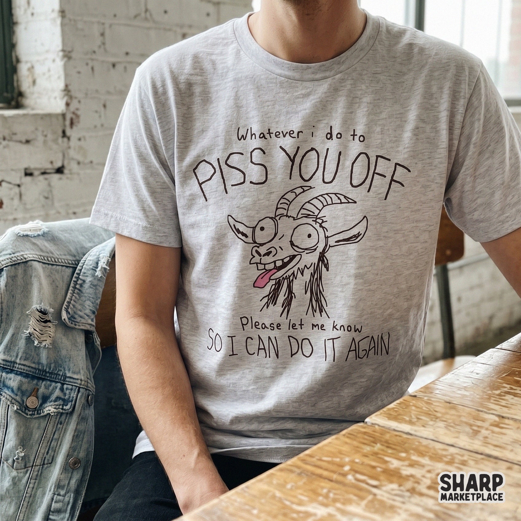 A sarcastic goat illustration on a heather grey t-shirt, featuring a chaotic hand-drawn farm animal and the text Whatever I do to piss you off so I can do it