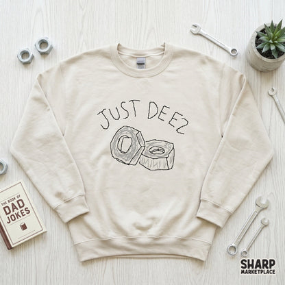 Beige crewneck sweatshirt featuring a minimalist hand-drawn illustration of two hardware nuts and the playful text Just Deez for a sarcastic look.