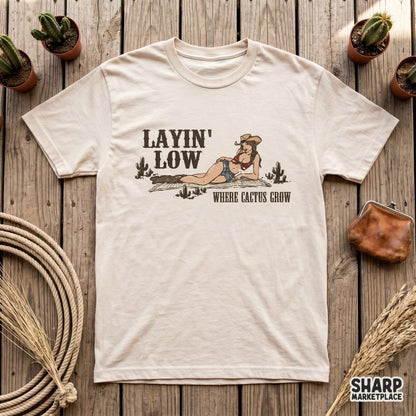 Digital western art file for apparel featuring a hand-drawn cowgirl lounging on a rug surrounded by desert cacti with distressed vintage typography.