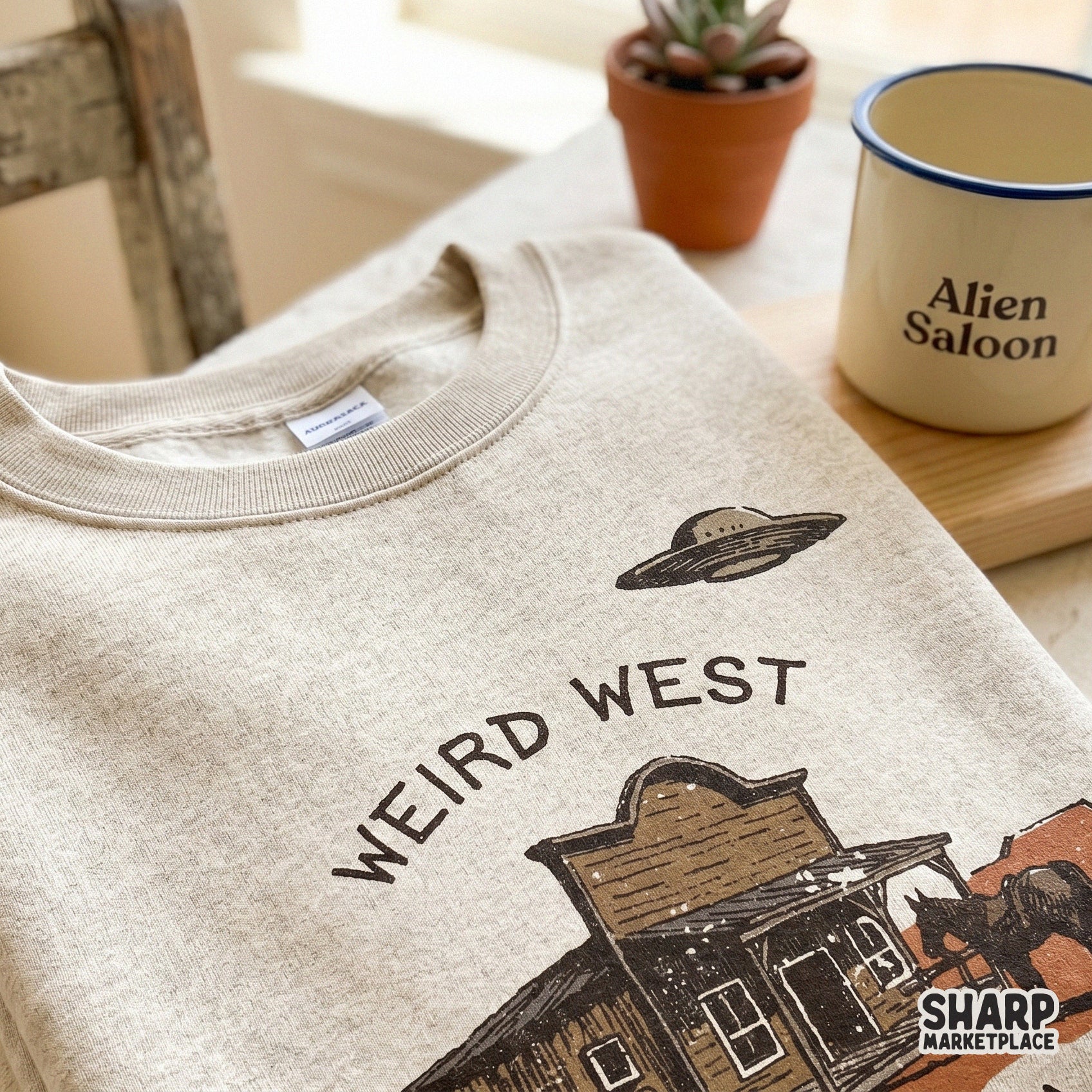 Vintage aesthetic western graphic with a desert saloon and UFO, designed for custom t-shirts, tumblers, and unique cosmic cowgirl themed projects.