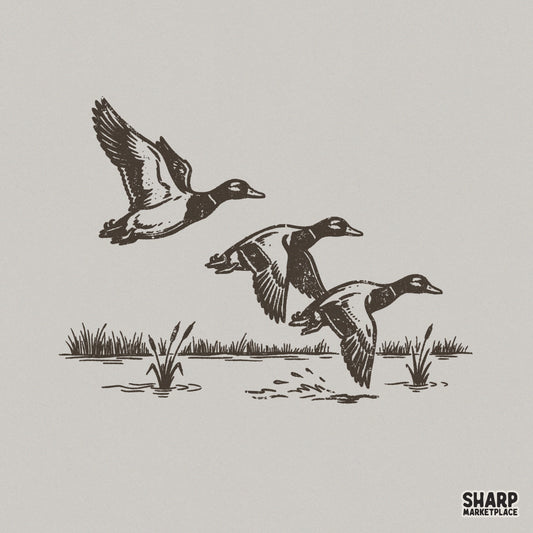 Vintage black ink illustration of three ducks taking flight over a marshy pond with cattails, isolated on a light gray background for apparel printing.