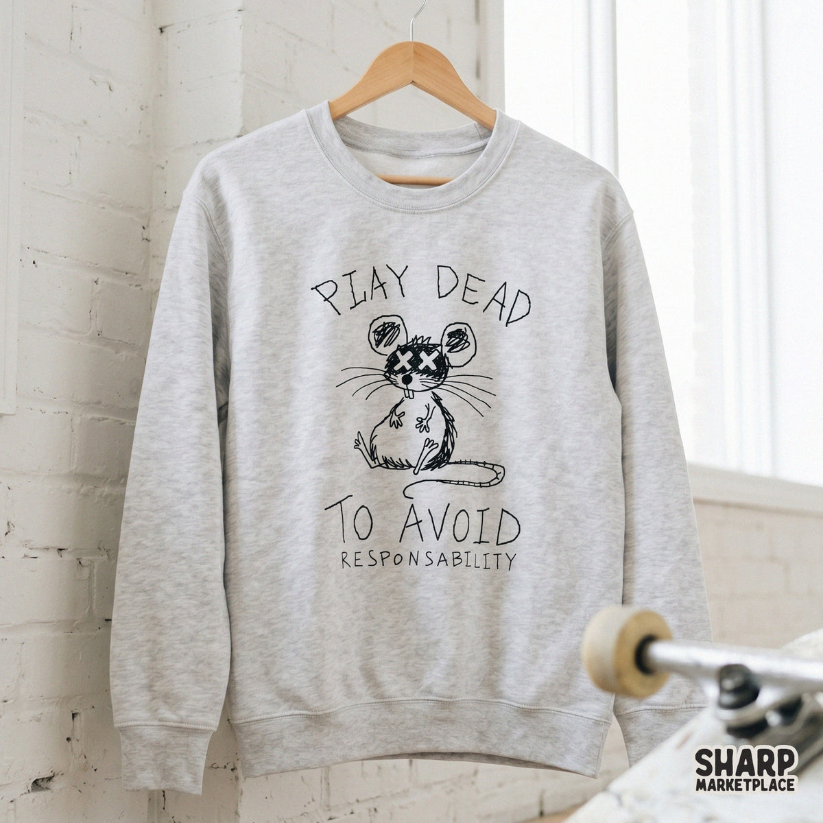 A light gray sweatshirt mockup featuring a black ink doodle of a faking-dead mouse with the sarcastic quote Play Dead To Avoid Responsibility printed on it.