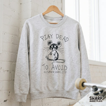 A light gray sweatshirt mockup featuring a black ink doodle of a faking-dead mouse with the sarcastic quote Play Dead To Avoid Responsibility printed on it.