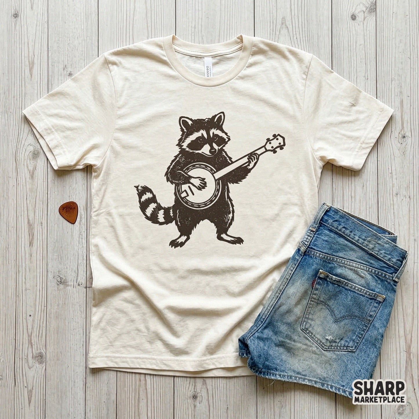 Apparel mockup showcasing a dark brown raccoon playing a banjo design printed on a cream-colored t-shirt, perfect for folk music themed clothing.