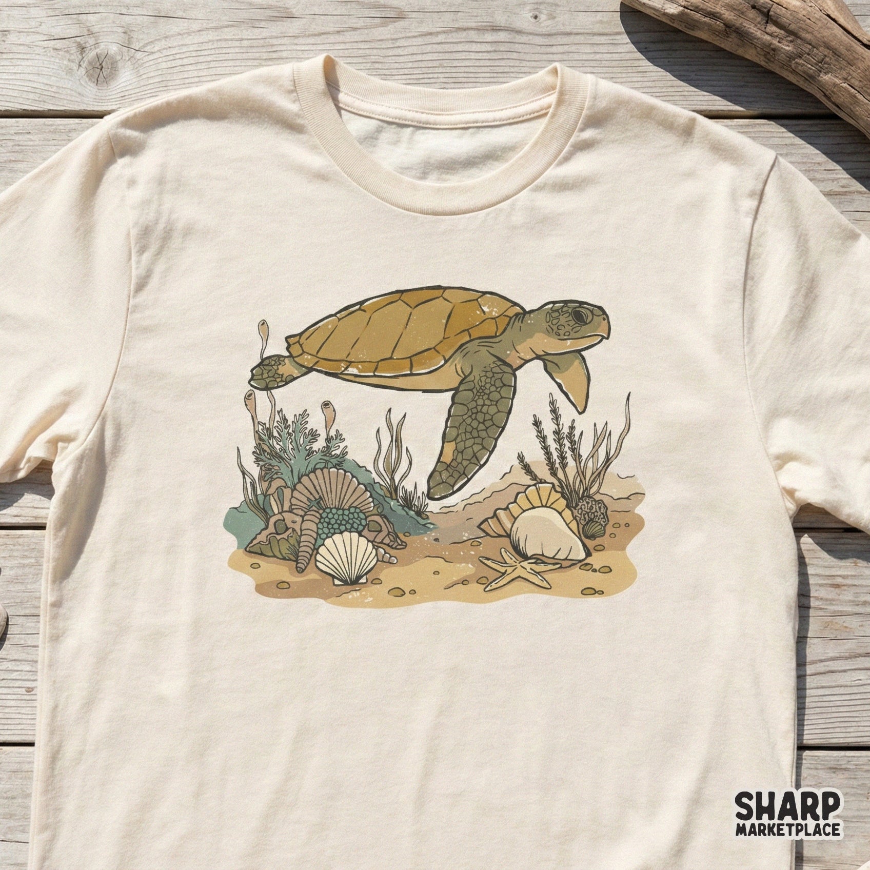 Vintage-style sea turtle illustration printed on a cream-colored t-shirt, featuring a detailed underwater scene with shells and marine plants.