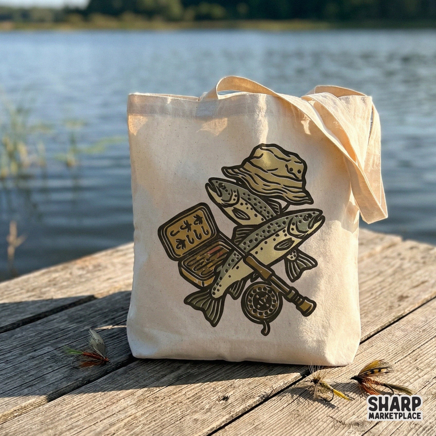 Rustic outdoor fishing illustration on a canvas tote bag, showcasing a fly rod, bucket hat, and trout in a distressed, block-print style.
