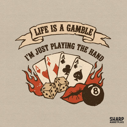 Retro poker themed digital design with four aces, dice, flames, an eight ball, and red lips, featuring the text Life Is A Gamble I'm Just Playing The Hand.