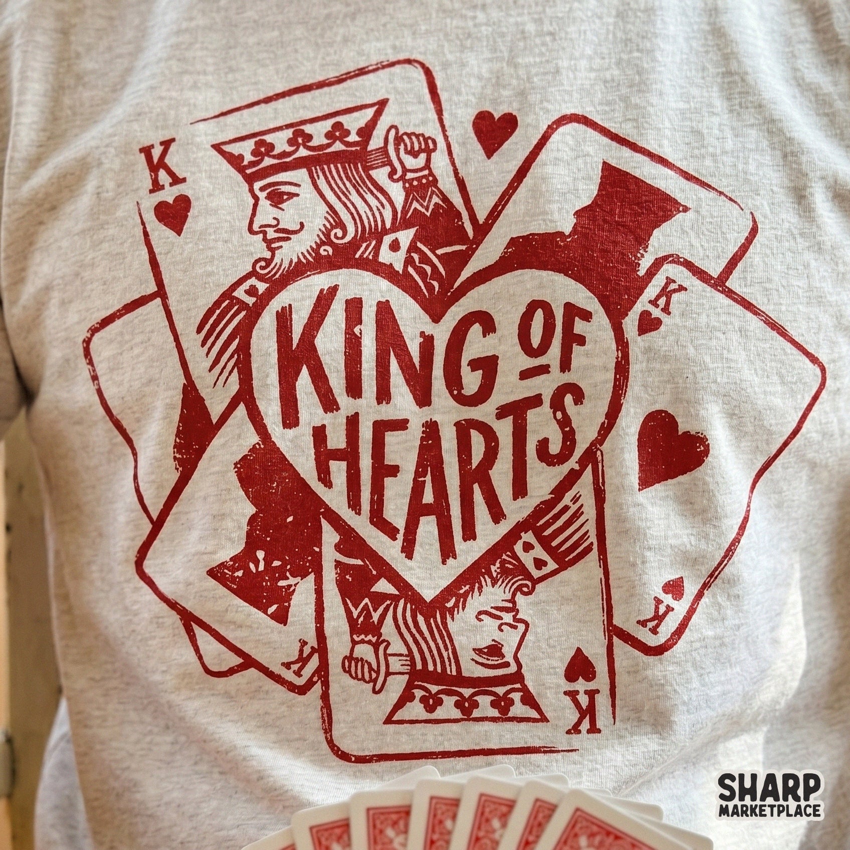 Vintage style King of Hearts graphic printed on a heather gray t-shirt, showcasing a distressed red ink playing card and heart illustration.