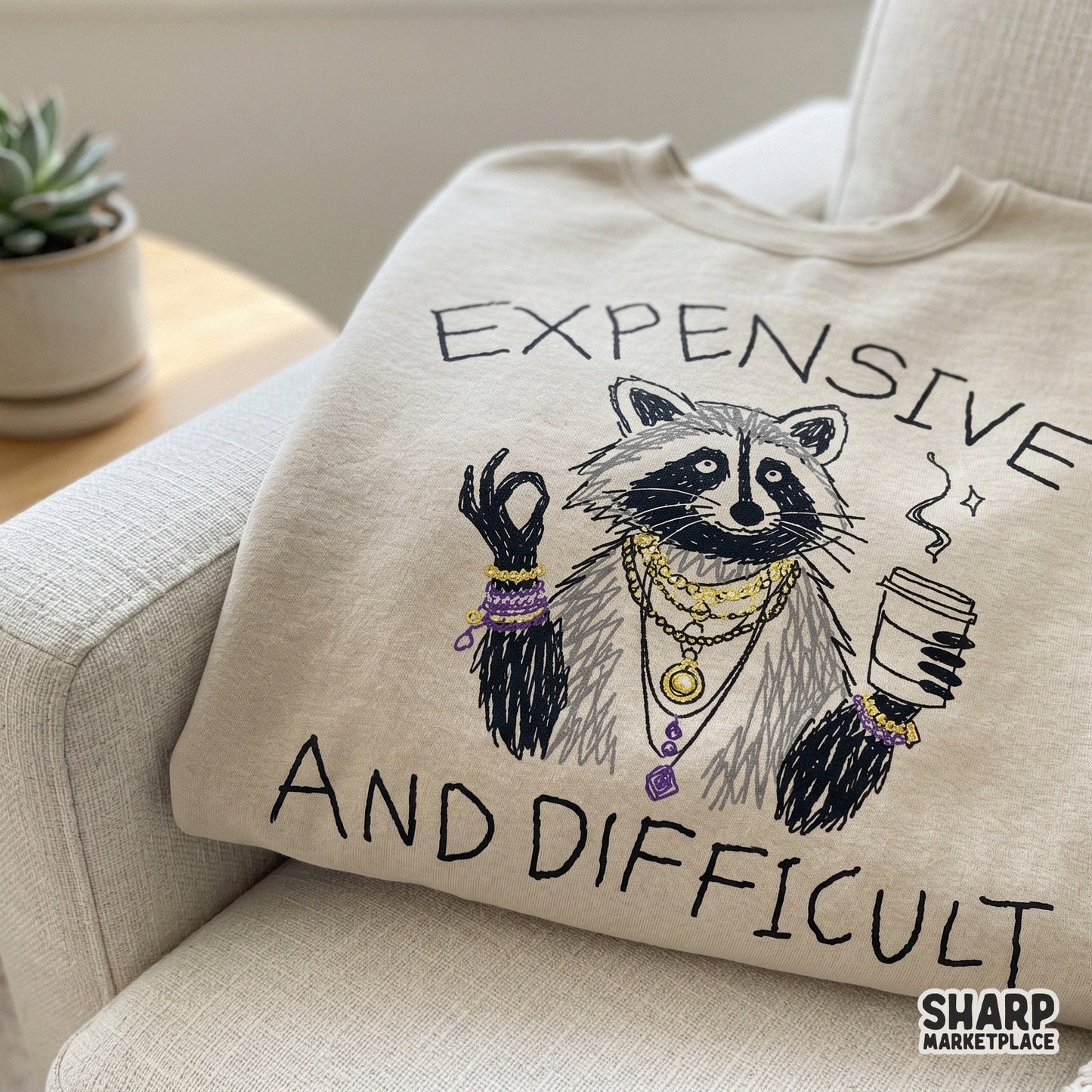 Funny animal meme design for apparel featuring a sketchy raccoon character, gold jewelry, and the handwritten quote Expensive And Difficult in black ink.