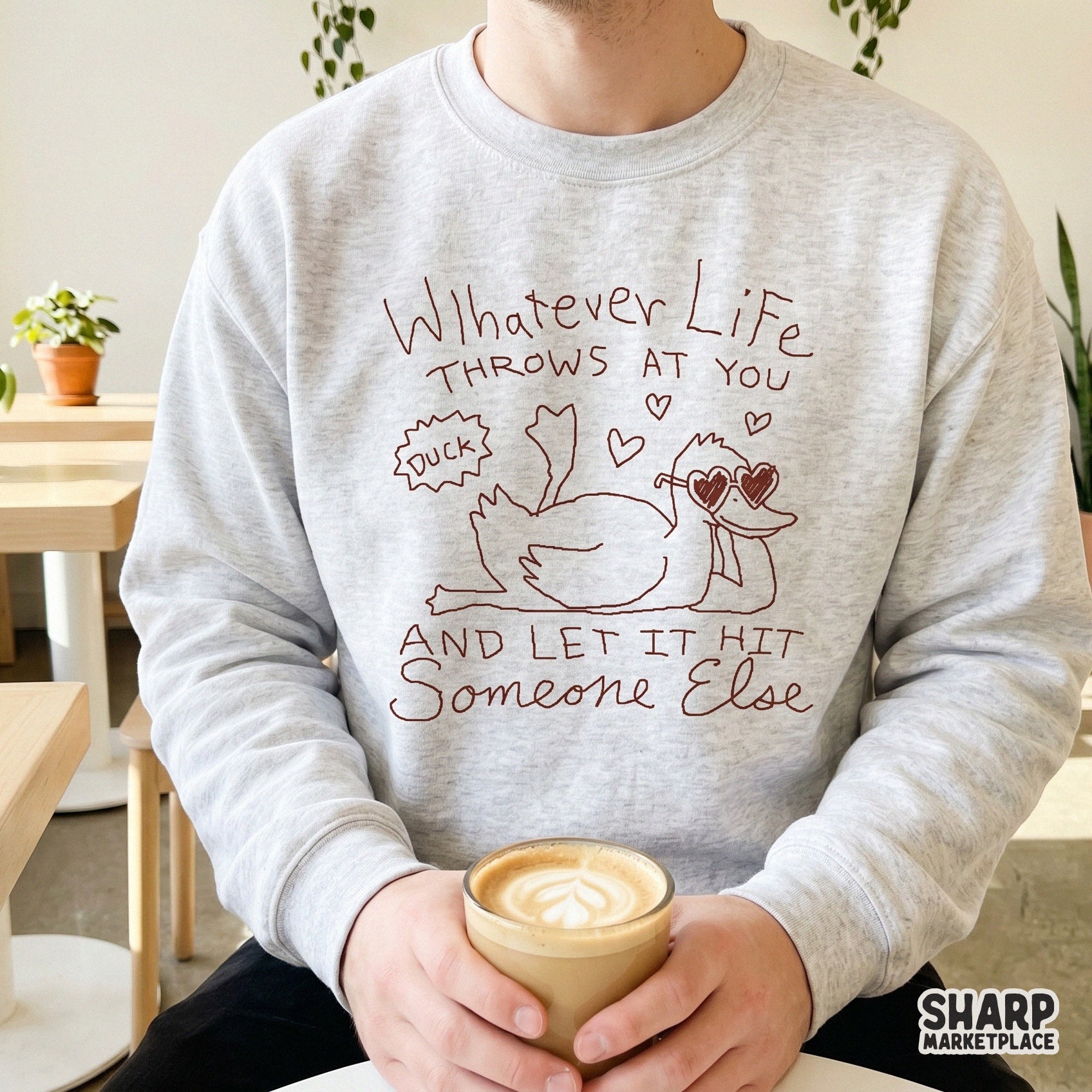 Sarcastic duck digital design on a light gray sweatshirt, featuring a lounging duck in heart-shaped glasses with the text Whatever Life Throws At You.