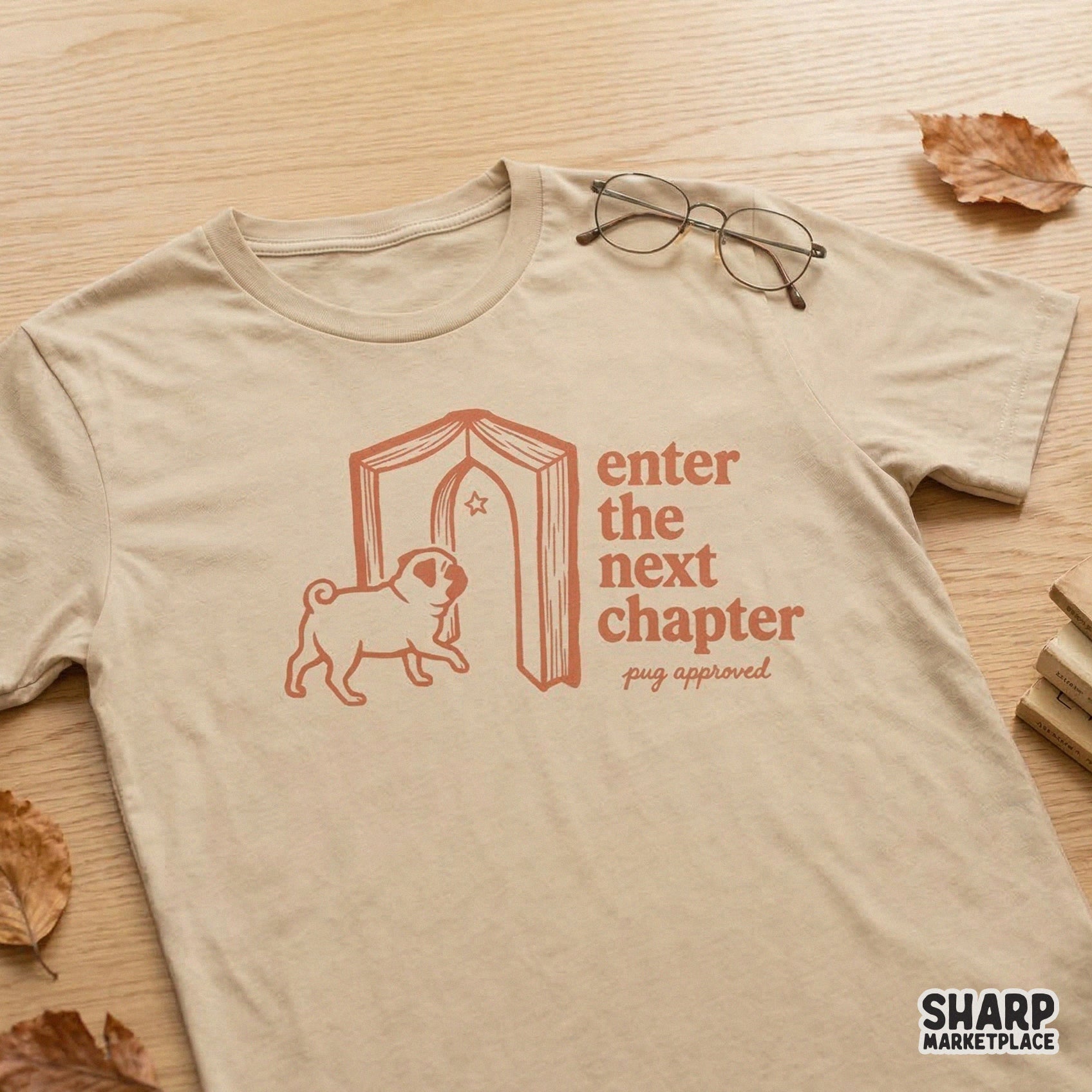 A tan t-shirt mockup showcasing a terracotta colored graphic of a pug entering an open book doorway with the text Enter the next chapter pug approved.