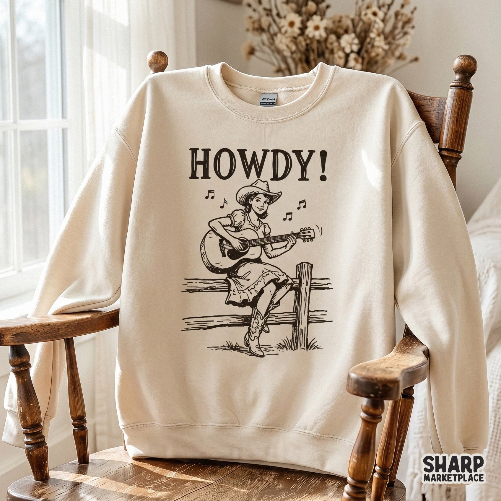 Trendy western cowgirl illustration with guitar and musical notes, showcased as a dark brown graphic on a light beige sweatshirt for apparel design.