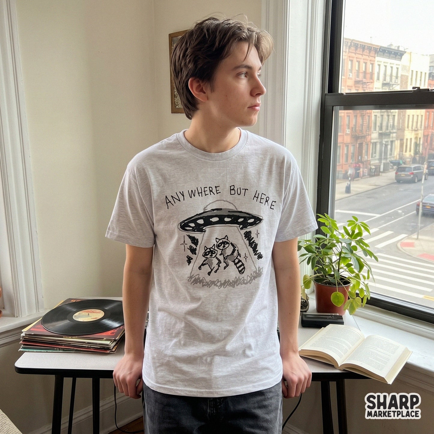 Hand-drawn style graphic of a raccoon UFO abduction with the sarcastic phrase Anywhere But Here, suitable for trendy print-on-demand products.