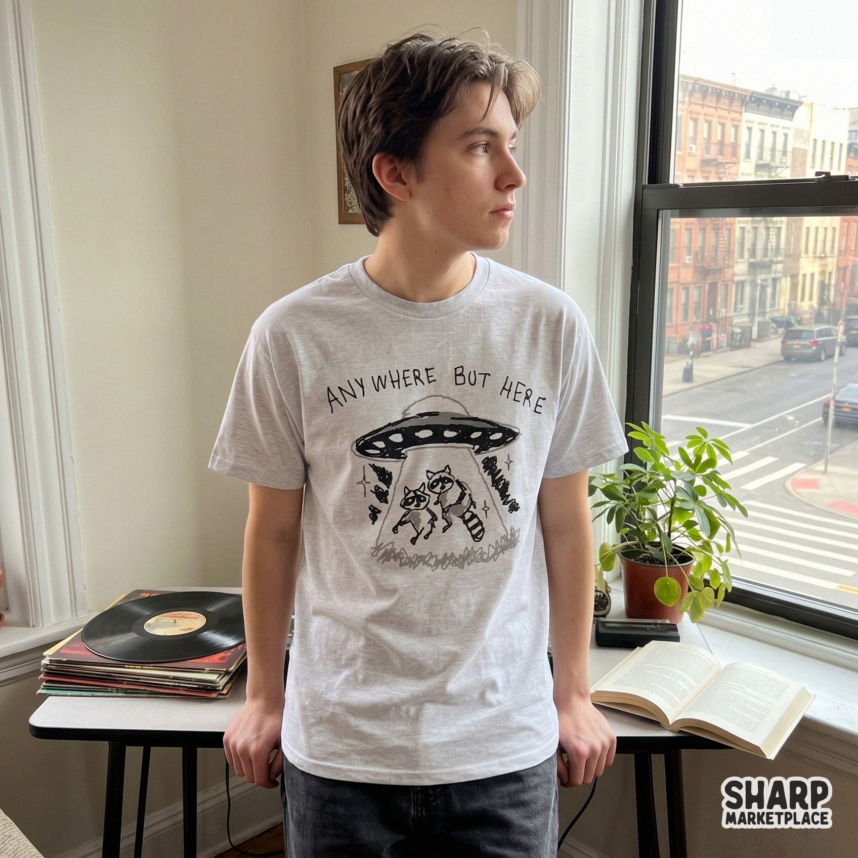 Hand-drawn style graphic of a raccoon UFO abduction with the sarcastic phrase Anywhere But Here, suitable for trendy print-on-demand products.