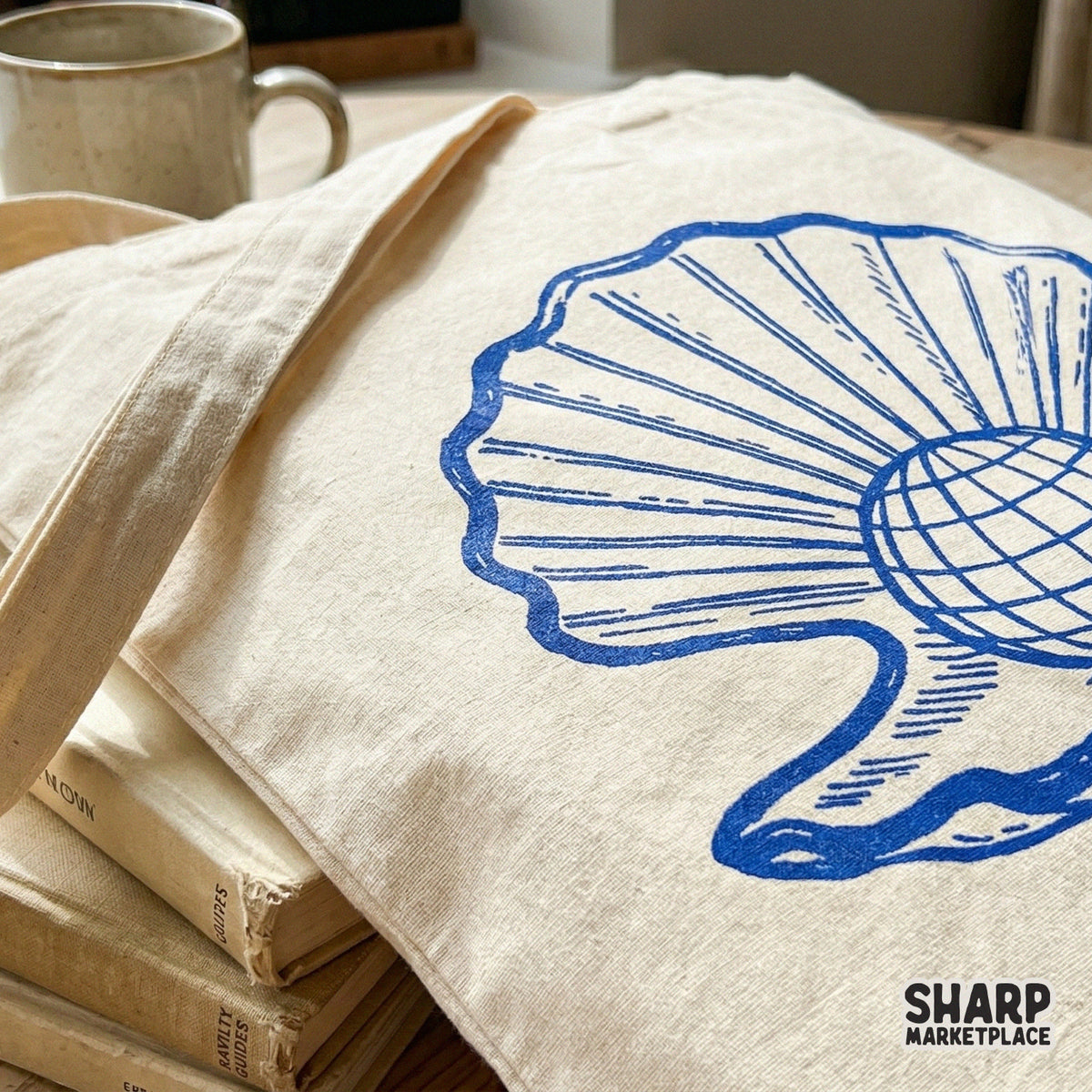 Close-up of a blue ink sketch of a shell with a globe inside, printed on a canvas tote bag for a trendy, minimalist summer aesthetic.