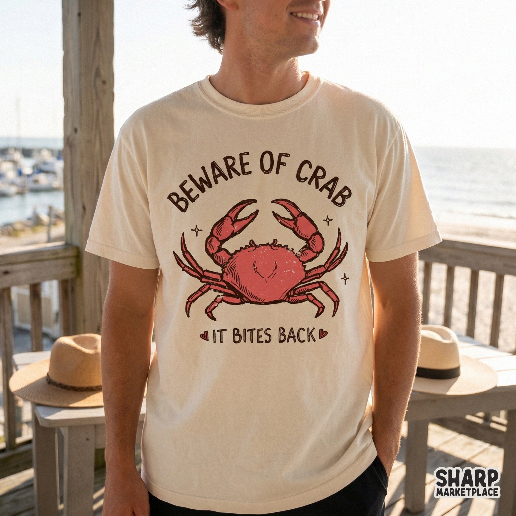 A vintage-style beach design featuring a red crab with raised claws and the sarcastic phrase Beware Of Crab It Bites Back on a cream-colored shirt.