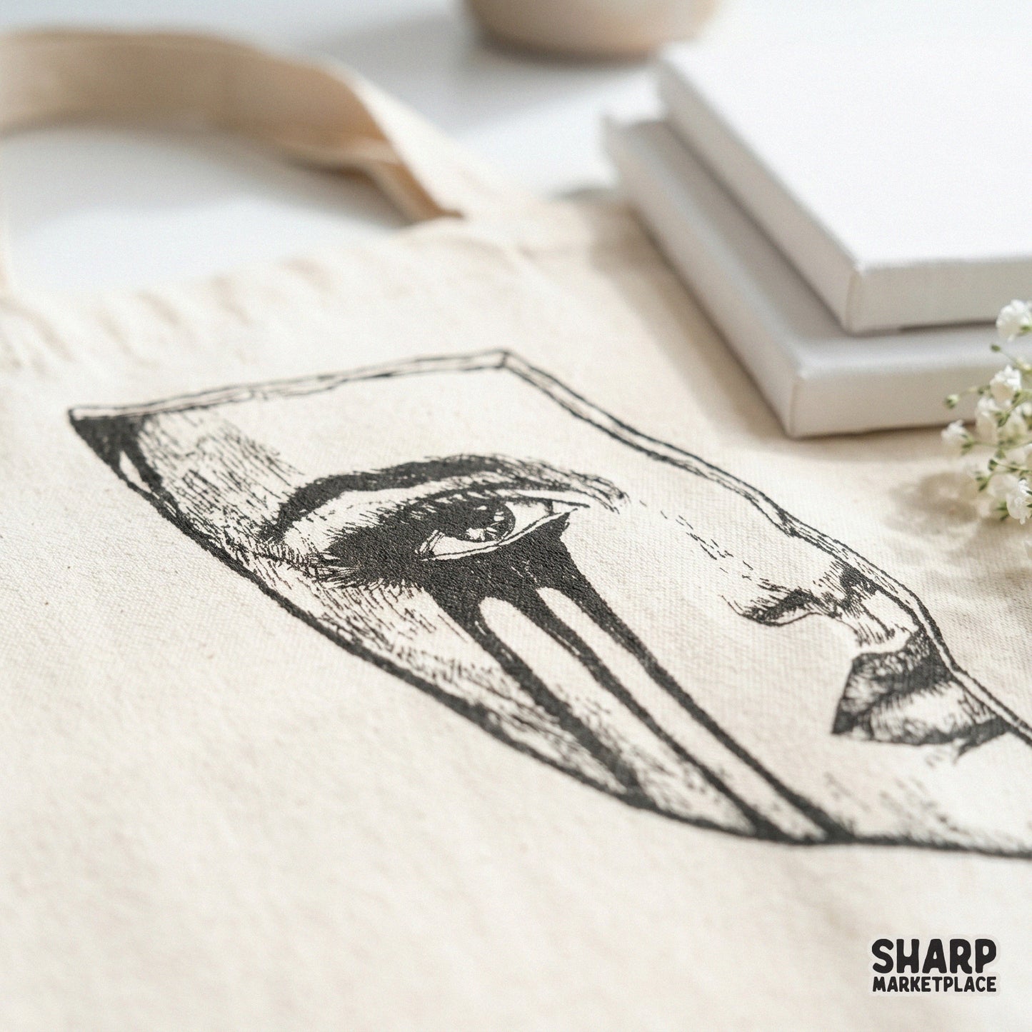 Close-up of a dark grunge crying mask design printed on a canvas tote bag, featuring sketchy line art for a trendy emo aesthetic.