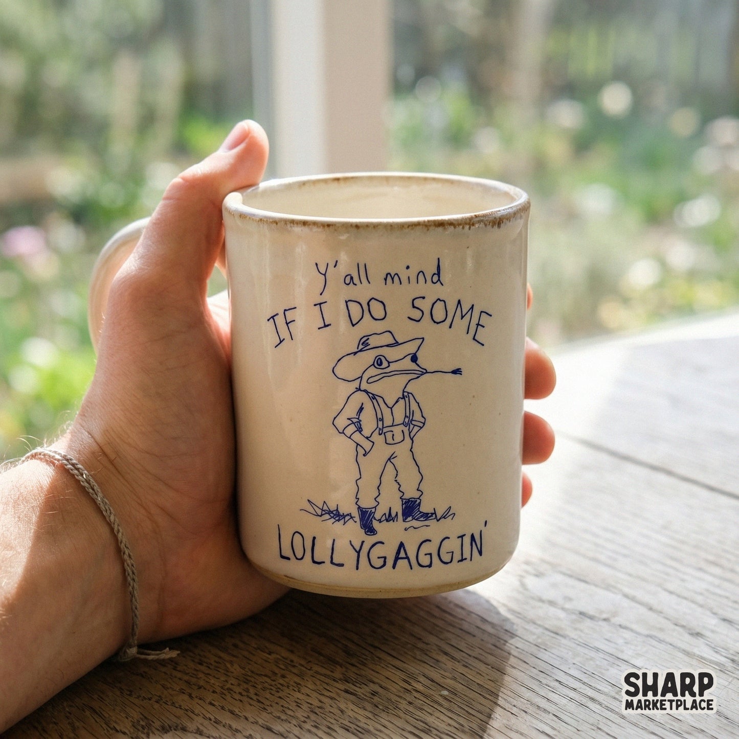 A ceramic mug featuring a blue line art illustration of a cowboy toad chewing hay with the sarcastic text Y'all mind if I do some lollygaggin'.