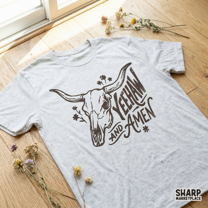 Vintage western bull skull graphic with floral sprigs and Yeehaw and Amen typography, shown printed on a light heather gray t-shirt.