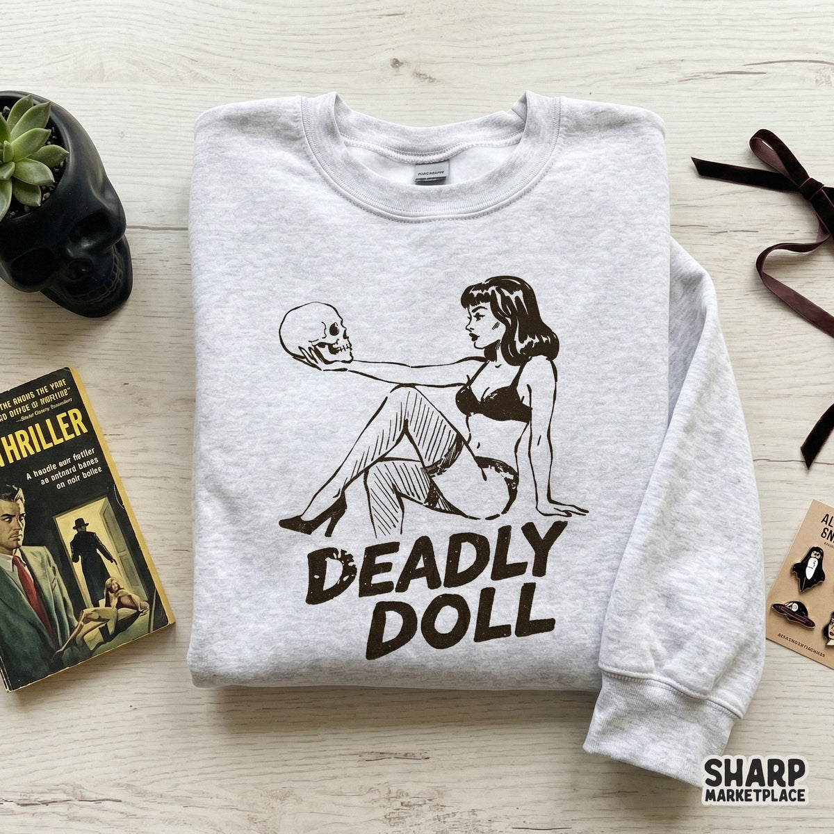 Gothic pinup girl holding a skull with bold distressed typography for dark humor sublimation designs and spooky Halloween apparel.