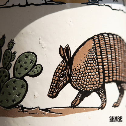 Vintage armadillo walking past a prickly pear cactus desert scene, western png sublimation design for t-shirts