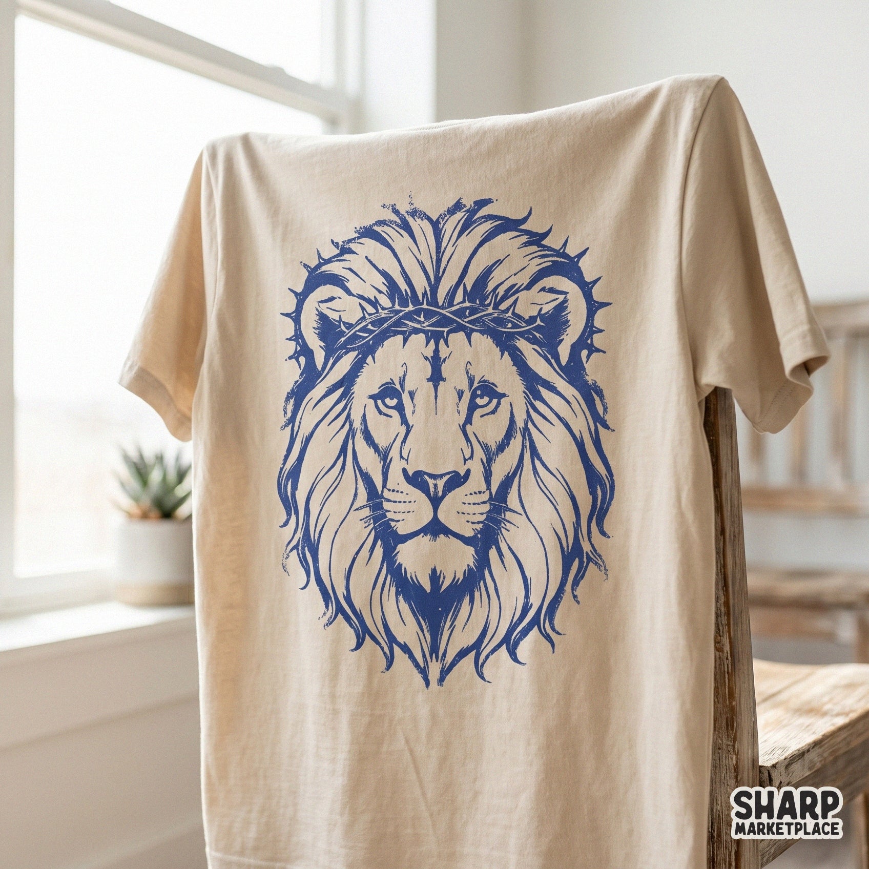 Monochromatic blue lion portrait with a crown of thorns displayed on a beige t-shirt mockup, ideal for religious graphic tees and custom apparel.