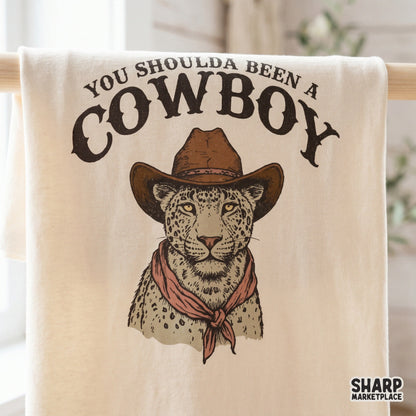 Western-themed digital design on a fabric mockup featuring a spotted leopard in a cowboy hat and bandana with rustic, distressed typography.