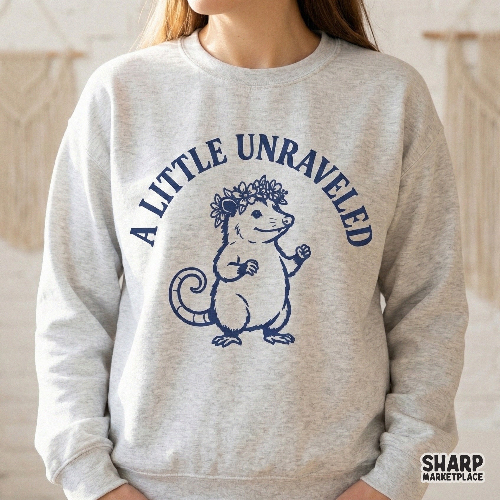 Digital sublimation design showing a hand-drawn opossum with a floral wreath and the phrase A Little Unraveled, ideal for custom t-shirts and stickers.