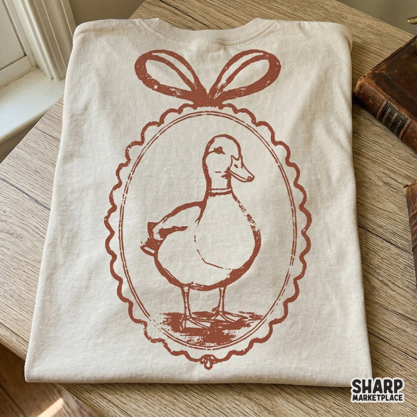 Charming hand-drawn duck cameo graphic with a ribbon bow, ideal for creating trendy spring-themed t-shirts, stickers, and farmhouse wall art.