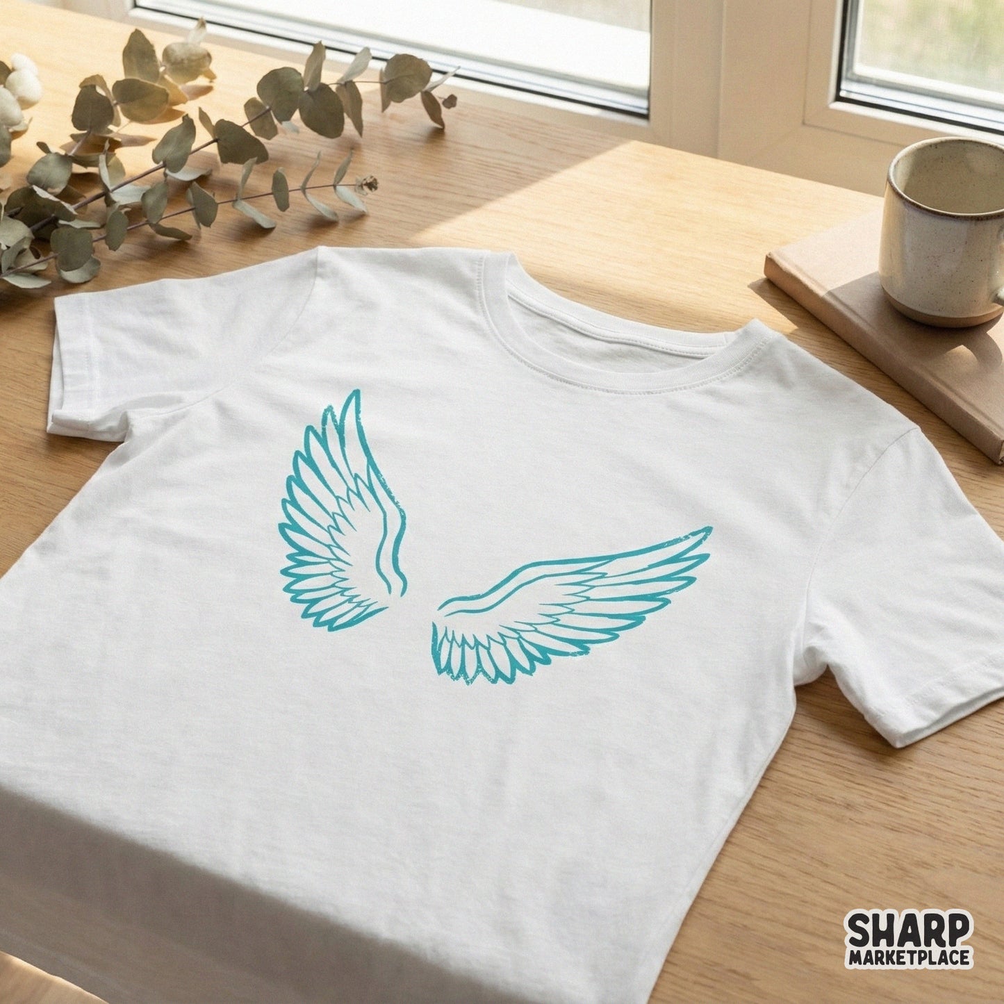 Teal blue angel wings graphic printed on a white t-shirt, showcasing a clean, artistic feather design suitable for apparel sublimation.