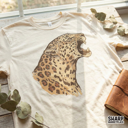 Roaring leopard digital design printed on a cream-colored t-shirt, showcasing a fierce big cat illustration for custom apparel.