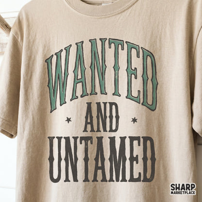 Vintage rodeo style Wanted and Untamed graphic displayed on a tan t-shirt, featuring western serif fonts and star accents for country fashion.