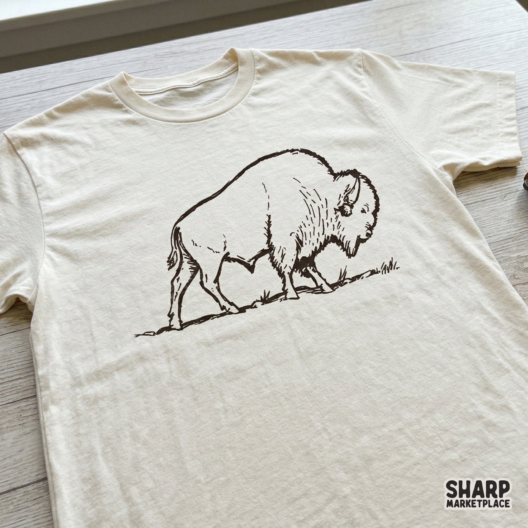 Vintage bison illustration printed on a cream t-shirt, showcasing a minimalist monochrome buffalo design perfect for western-inspired clothing.