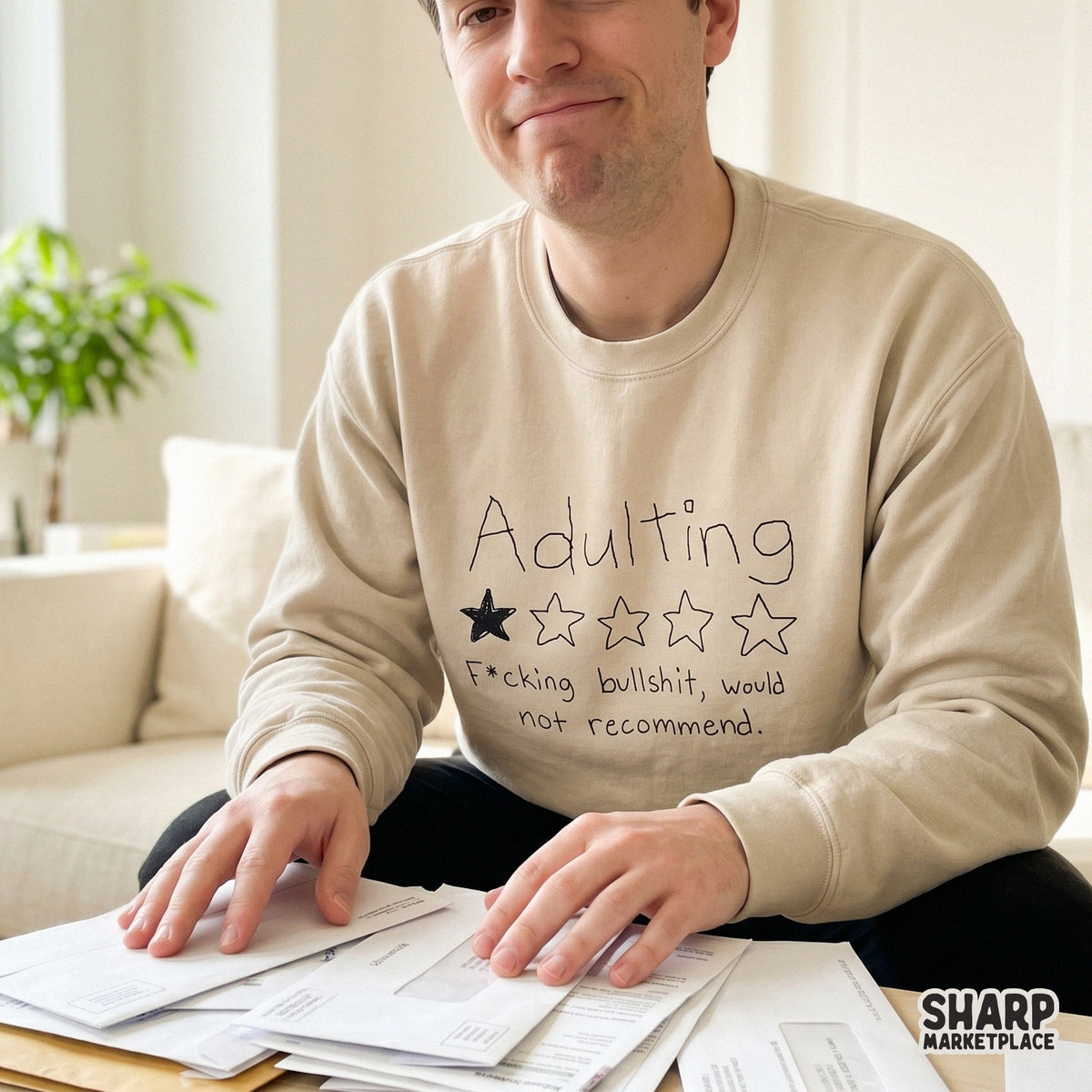 A beige sweatshirt featuring a black hand-drawn design of a one-star rating for adulting with the text F-cking bullshit, would not recommend.