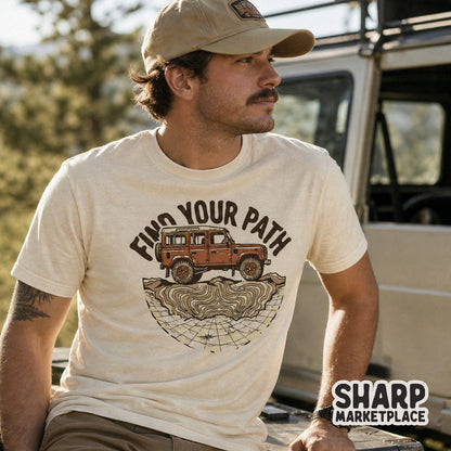 A man wearing a cream t-shirt with a vintage-style off-road truck graphic, topographic map details, and the inspirational text Find Your Path.