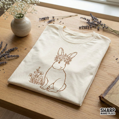 A monochromatic sepia floral rabbit design printed on a folded cream-colored t-shirt, showcasing a woodland animal with a wildflower crown.