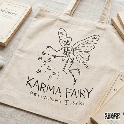 Tote bag featuring a black line art design of a skeleton fairy with butterfly wings dropping skulls, with the text Karma Fairy Delivering Justice below.