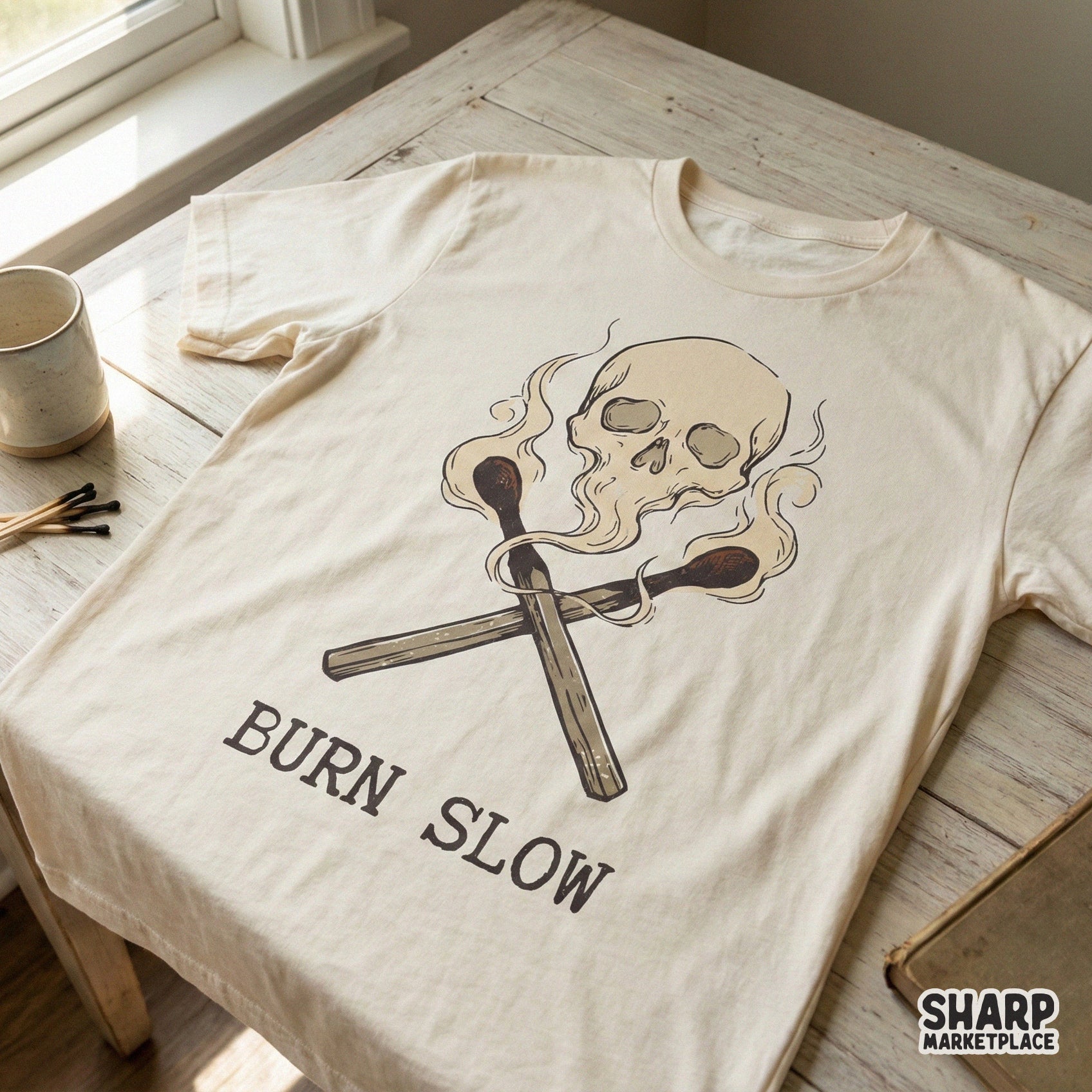 Retro style digital design featuring a skull emerging from smoke above crossed matches with the phrase Burn Slow for custom t-shirt printing.