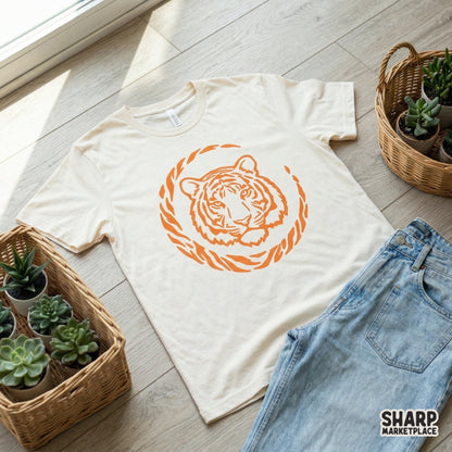 Trendy orange tiger head illustration with a circular jungle stripe border, shown as a digital design on a light-colored t-shirt mockup.