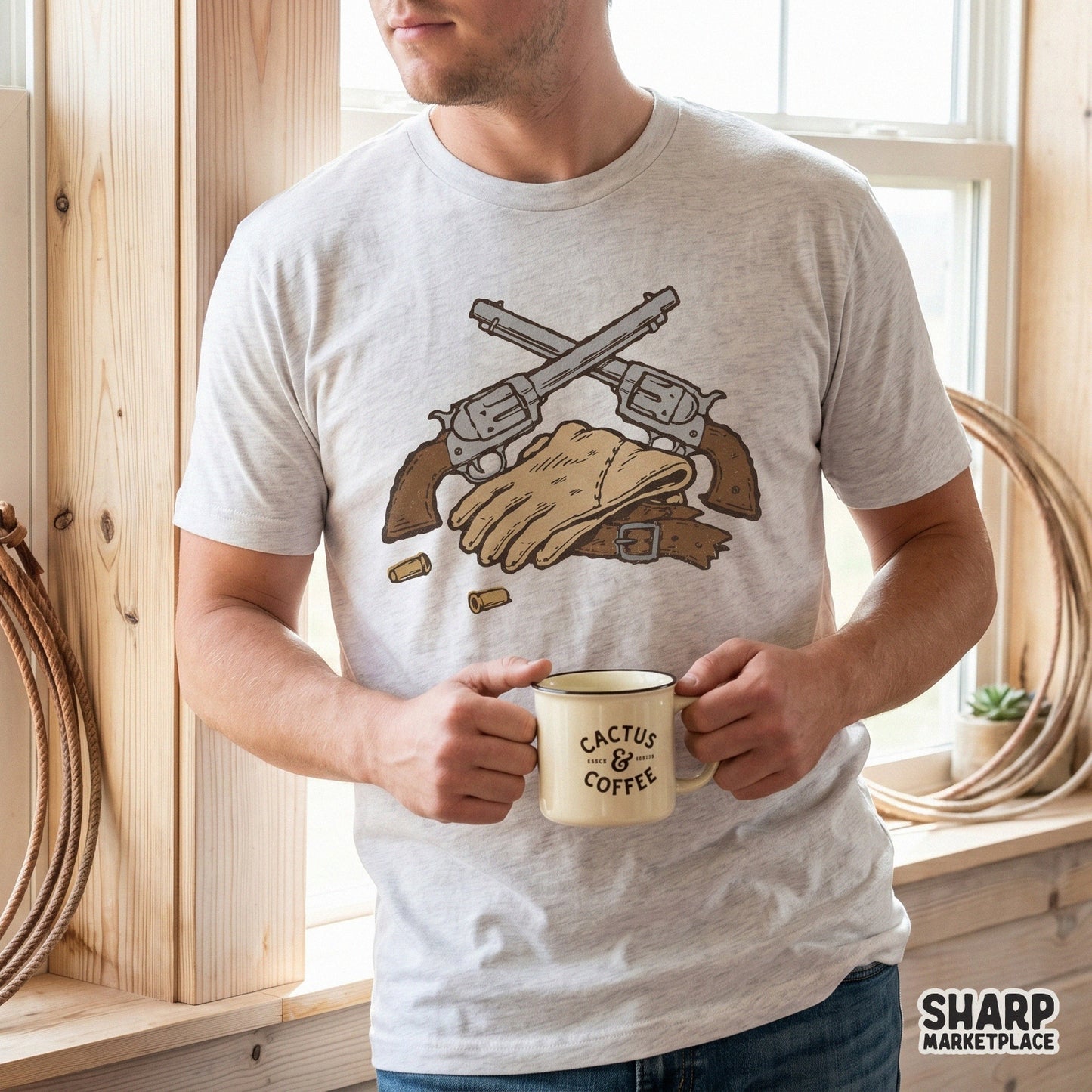 Rustic cowboy graphic with crossed pistols and leather gear displayed on a light heather t-shirt for western-themed apparel and print projects.